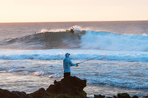 Fisherman and surfer at Rocky Point on Oahu's North Shore